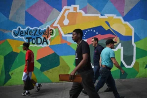 Moradores de Caracas passam por mural convocando o referendo sobre Essequibo, incluída no mapa da Venezuela pintado na propaganda - Federico Parra - 28.nov.2023/AFP